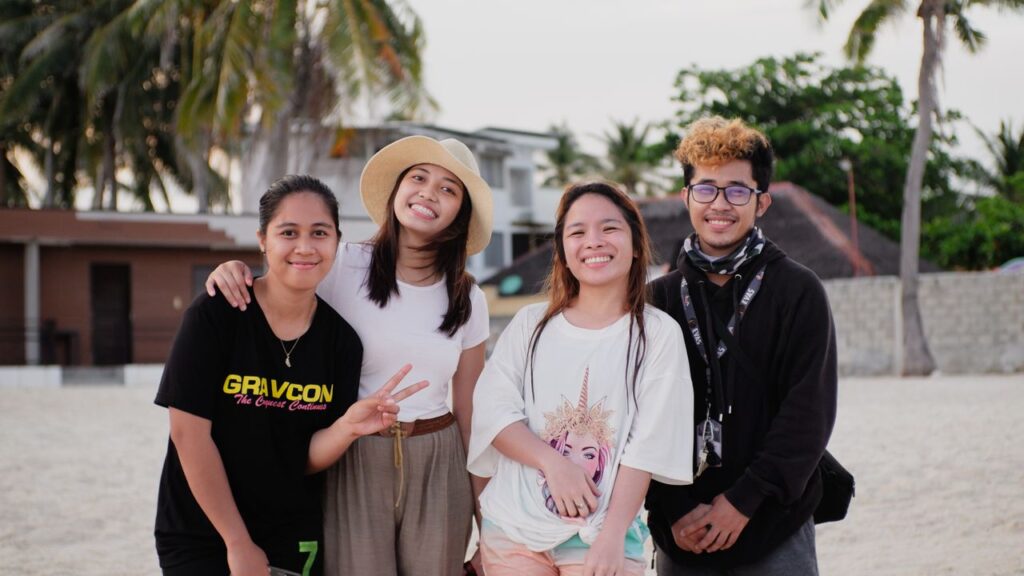 Happy group of friends smiling and bonding at the beach under palm trees.